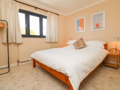 A bedroom with a bed two framed pictures and a clothes rack at Auverne in Poundstock near Widemouth Bay