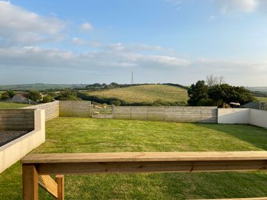 A garden with wooden and concrete fencing and a view of hills at Auverne in Poundstock near Widemouth Bay