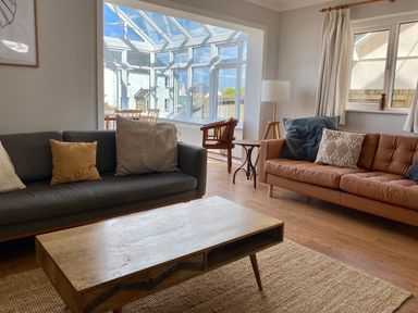 A living room with two sofas a wooden coffee table a floor lamp and a window at Auverne Poundstock near Widemouth Bay