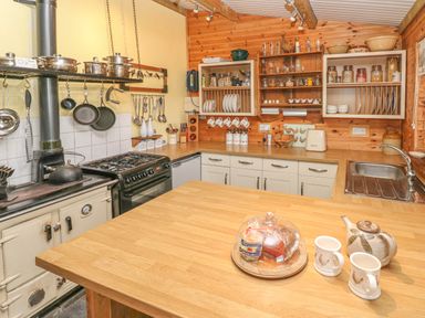 A kitchen with wooden countertops pots hanging on a rack and shelves with jars at Sarngwm in Narberth