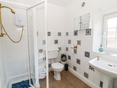 A bathroom with a shower, toilet, sink, and window at The Vale in Ashwater