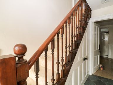 A wooden staircase with carpeted steps and a white door underneath at The Vale in Ashwater