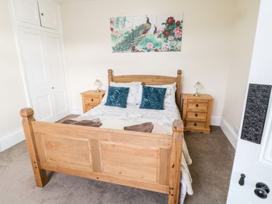 A bedroom with a wooden bed and matching bedside tables with lamps at The Vale in Ashwater