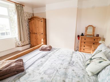 A bedroom with a wooden bed and dresser and a wardrobe near a window at The Vale in Ashwater
