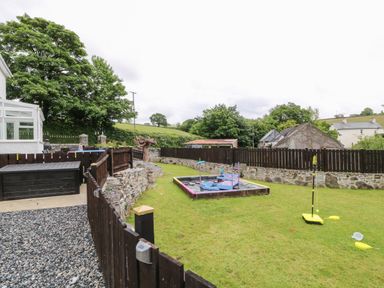 A garden area with a fenced sandbox and a toy badminton set at The Vale in Ashwater