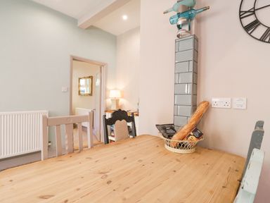 A wooden dining table with chairs and a basket with bread and snacks in a room at Saxon Lodge Cottage Felixstowe Suffolk