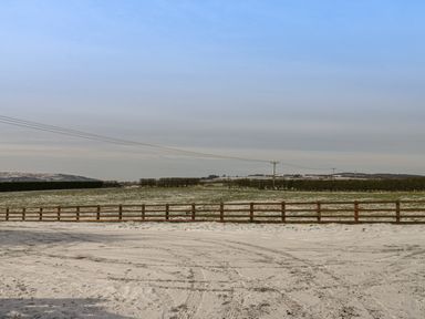 A snow-covered field with wooden fence and power lines at Shipswheel Cottage at Broadings Farm Whitby