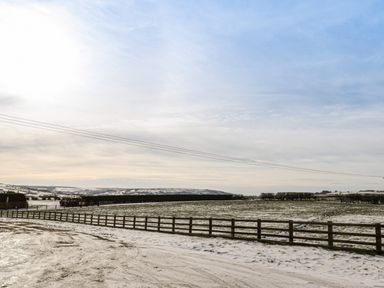 A snow-covered field with a wooden fence under a cloudy sky at Shipswheel Cottage at Broadings Farm in Whitby