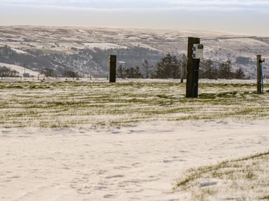 A snow-covered field with wooden posts and hills in the background at Shipswheel Cottage at Broadings Farm Whitby