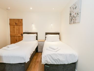 A bedroom with two single beds and a wooden door at Shipswheel Cottage at Broadings Farm Whitby