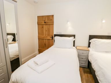 A bedroom with two single beds and a wooden door at Shipswheel Cottage at Broadings Farm in Whitby
