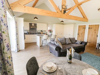 An open plan kitchen and living area with a dining table set with plates and champagne at Stag Cottage at Broadings Farm Whitby