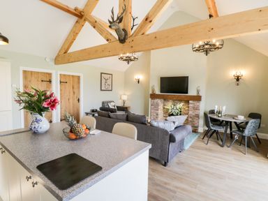 A living room with exposed wooden beams a sofa a fireplace and a dining table at Stag Cottage at Broadings Farm in Whitby