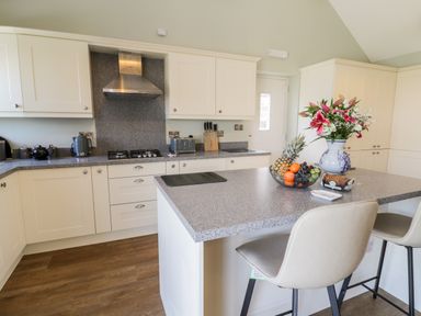 A kitchen with white cabinets a gray countertop a fruit bowl and a vase with flowers at Stag Cottage at Broadings Farm in Whitby