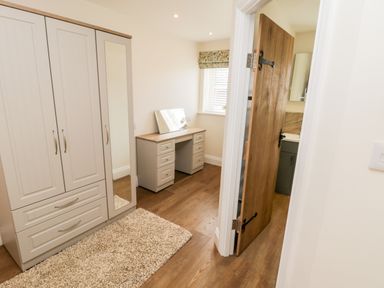 A dressing room with a wardrobe a desk and a wooden door at Stag Cottage at Broadings Farm in Whitby