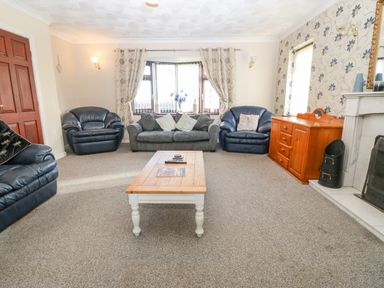 A living room with three armchairs a sofa coffee table and a wooden cabinet at Rhiangwyn in Llanrhyddlad near Cemaes Bay