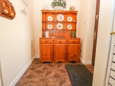 A wooden cabinet with decorative plates and plants in a hallway at Rhiangwyn Llanrhyddlad near Cemaes Bay
