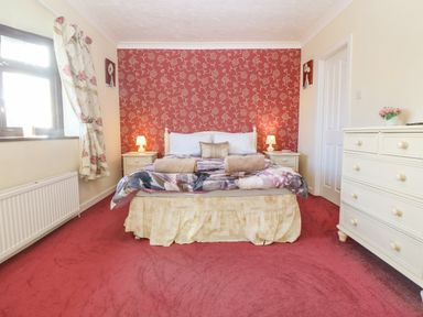 A bedroom with a double bed two bedside tables and lamps a chest of drawers and a window at Rhiangwyn in Llanrhyddlad near Cemaes Bay