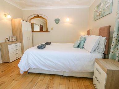 A bedroom with a bed white linens rolled towels bedside tables and a wardrobe at Rhiangwyn in Llanrhyddlad near Cemaes Bay