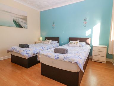 A bedroom with two single beds each with floral bedding and a rolled towel on top at Rhiangwyn in Llanrhyddlad near Cemaes Bay