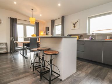 A kitchen and dining area with a kitchen island and stools at Box Tree Escapes in Kirkby Lonsdale