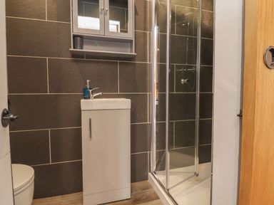 A bathroom with a toilet sink cabinet mirror cabinet and glass shower enclosure at Box Tree Escapes in Kirkby Lonsdale