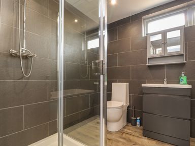 A bathroom with a shower enclosure toilet sink with cabinet and mirror at Box Tree Escapes in Kirkby Lonsdale