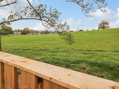 A view of green fields with a wooden fence and trees at Box Tree Escapes in Kirkby Lonsdale