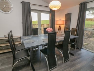 A dining room with a rectangular table set with placemats and surrounded by black chairs at Box Tree Escapes Wennington near Kirkby Lonsdale