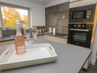 A kitchen with a bottle of Freixenet Italian rose and two glasses on a tray on the countertop at Box Tree Escapes Wennington near Kirkby Lonsdale