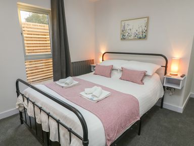 A bedroom with a bed with pink cushions and a pink runner with towels on the bed at Box Tree Escapes in Wennington near Kirkby Lonsdale