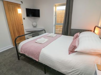 A bedroom with a bed towels a television and a window at Box Tree Escapes Wennington near Kirkby Lonsdale