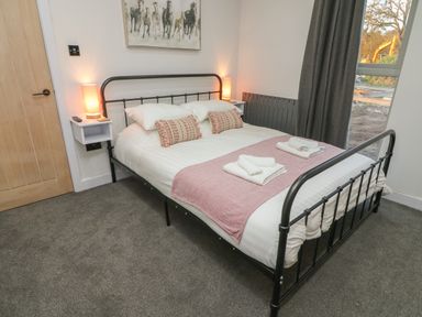 A bedroom with a metal bed frame two bedside lamps and a window with dark curtains at Box Tree Escapes Wennington near Kirkby Lonsdale