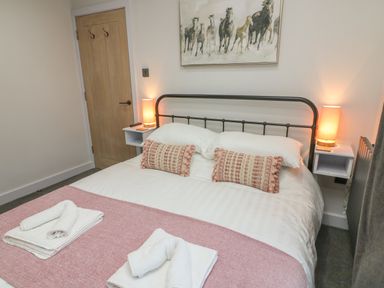 A bedroom with a double bed two bedside lamps and a painting of horses above the bed at Box Tree Escapes Wennington near Kirkby Lonsdale
