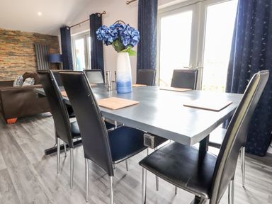 A dining room with a table and black chairs with a blue and white vase of flowers at Box Tree Escapes Wennington near Kirkby Lonsdale