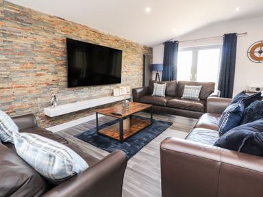 A living room with leather sofas table and wall mounted tv at Box Tree Escapes Wennington near Kirkby Lonsdale