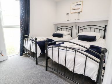 A bedroom with two single metal frame beds with white bedding and dark blue cushions at Box Tree Escapes Wennington near Kirkby Lonsdale