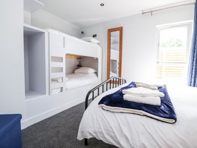 A bedroom with bunk beds a double bed a mirror and a window at Box Tree Escapes Wennington near Kirkby Lonsdale