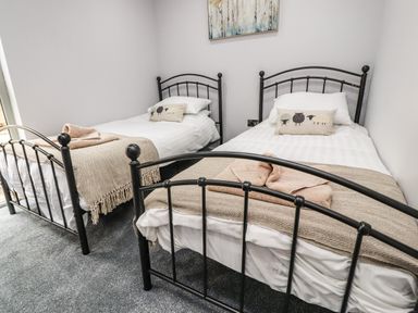A bedroom with two single beds with black metal frames and beige blankets at Box Tree Escapes in Wennington near Kirkby Lonsdale