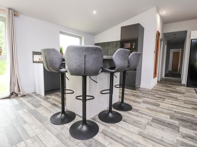 A kitchen island with four bar stools and wooden flooring at Box Tree Escapes in Wennington near Kirkby Lonsdale