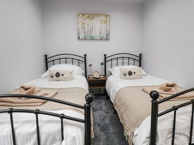 A bedroom with two single beds with black metal frames a nightstand with two lamps and a painting on the wall at Box Tree Escapes in Wennington near Kirkby Lonsdale