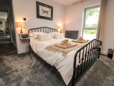 A bedroom with a double bed two lamps a window and wall art at Box Tree Escapes in Wennington near Kirkby Lonsdale