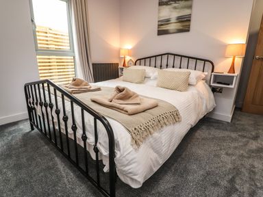A bedroom with a black metal bed frame and beige pillows at Box Tree Escapes in Wennington near Kirkby Lonsdale