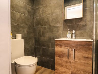 A bathroom with a toilet and a wooden vanity with a sink at Box Tree Escapes in Wennington near Kirkby Lonsdale
