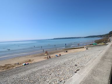 A beach with pebbles and sand and people by the water at Oakland Cottage in Summerhill near Saundersfoot