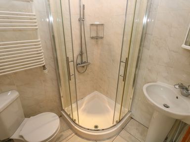 A bathroom with a corner shower enclosure toilet a sink and a towel radiator at Oakland Cottage in Summerhill near Saundersfoot