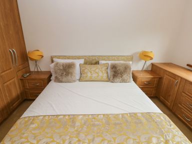 A bedroom with a bed with white and yellow bedding cushions and wooden bedside tables with yellow lamps Oakland Cottage Summerhill near Saundersfoot