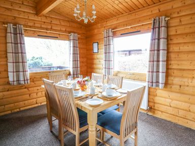 A dining room with a wooden table set for six at Valley View in Rhayader