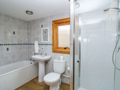 A bathroom with a bathtub sink toilet shower and a wooden framed window at Valley View in Rhayader