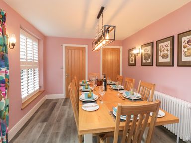 A dining room with a wooden table and chairs set with plates glasses and pears on napkins at Hazelnut Cottage in Windermere
